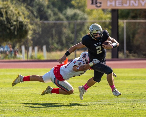 Butte College quarterback Rieger Sayre (2) runs the ball as American River's Josh Tremain (left) goes in for a sack during the Butte vs. American River football game on Saturday Oct. 21, 2023 at Cowan Stadium in Butte Valley, California. (Ben Mota/All Axis Sports -- Contributed)